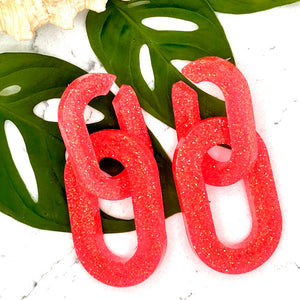 All Up In The Hair | Online Accessory Boutique Located in Mooresville, NC | Two Coral Chunky Chain Earrings laying on two monstera leaves. The leaves are laying on a white background.