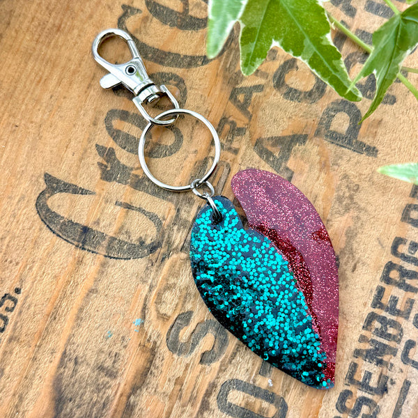 All Up In The Hair | Online Accessory Boutique Located in Mooresville, NC | Back of our Alocasia Half Moon Key Chain on a wood background with black lettering.