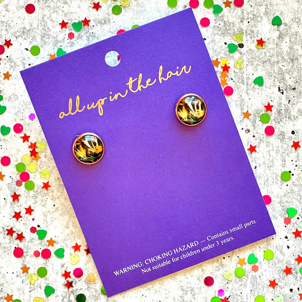 All Up In The Hair | Online Accessory Boutique Located in Mooresville, NC | An indigo colored, All Up In The Hair branded packaging laying on a gray background, surrounded by colorful glitter. On the card is two Bird Of Paradise Earrings.
