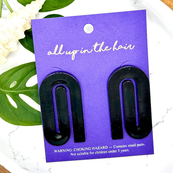 All Up In The Hair | Online Accessory Boutique Located in Mooresville, NC | Two Black Paperclip Earrings on an indigo backer card. The card is laying on two monstera leaves on a white background.