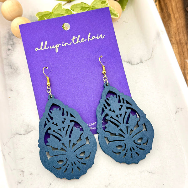 All Up In The Hair | Online Accessory Boutique Located in Mooresville, NC | Two Blue Floral Earrings on an indigo colored, All Up In The Hair branded packaging card. The card is laying on a white marble background.