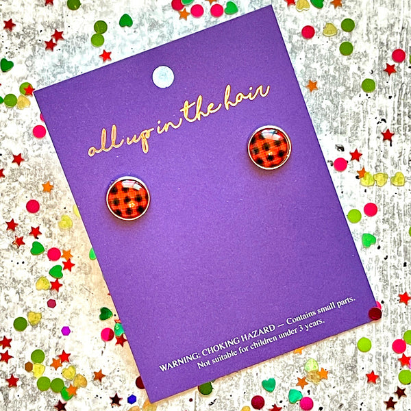 All Up In The Hair | Online Accessory Boutique Located in Mooresville, NC | An All Up In The Hair packaging card laying on a gray background, surrounded by colorful glitter. On the card is two buffalo plaid earrings.
