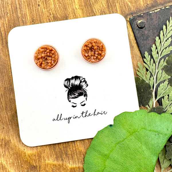 All Up In The Hair | Online Accessory Boutique Located in Mooresville, NC | Two camel druzies set in rose gold earring settings. The earrings are on a white, All Up In The Hair branded packaging card. The card is laying on a wood background next to green leaves.