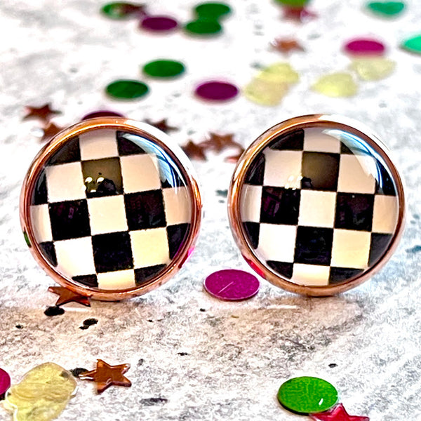 All Up In The Hair | Online Accessory Boutique Located in Mooresville, NC | Close up of two checkered flag earrings laying on a gray background, surrounded by colorful glitter.