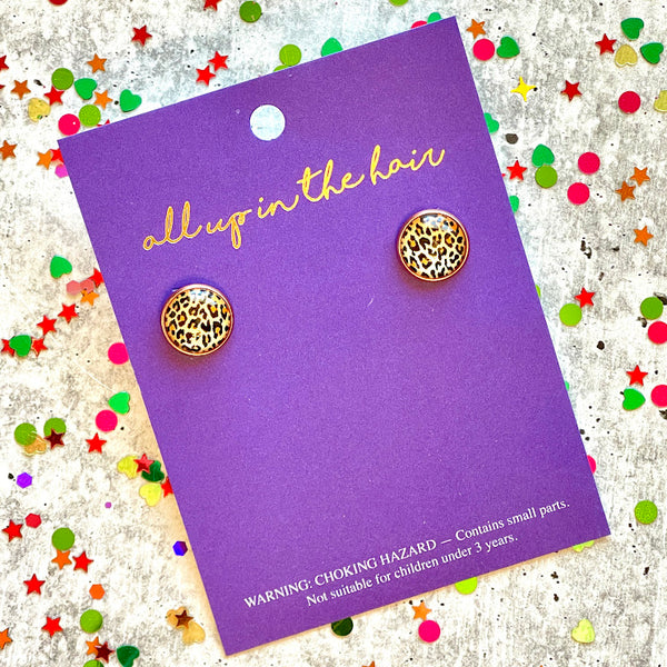 All Up In The Hair | Online Accessory Boutique Located in Mooresville, NC | An All Up In The Hair branded packaging card laying on a gray background, surrounded by colorful glitter. On the card is two cheetah earrings.