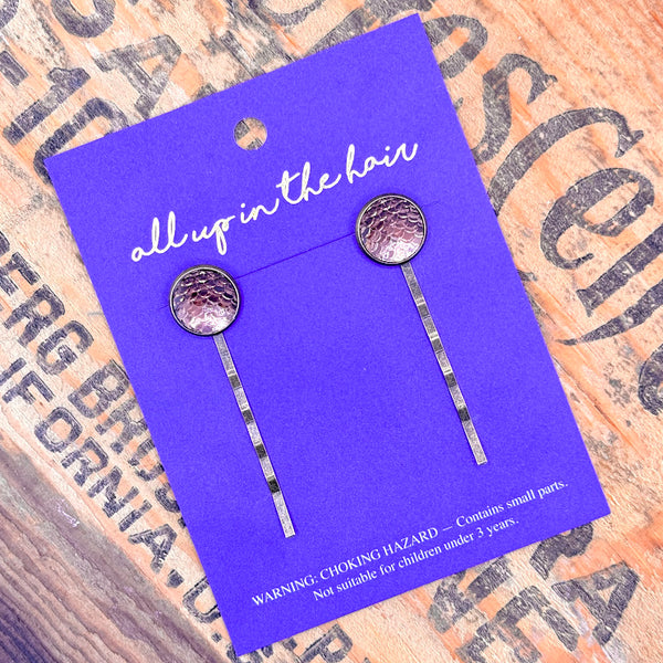 All Up In The Hair | Online Accessory Boutique Located in Mooresville, NC | Two Chocolate Brown Bobby Pins on an indigo colored, All Up In The Hair branded packaging card. The card is laying on a wood background with black lettering.