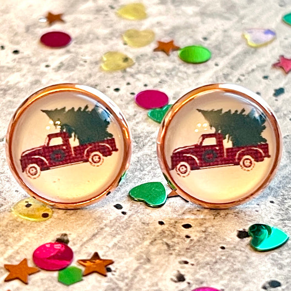 All Up In The Hair | Online Accessory Boutique Located in Mooresville, NC | Two Christmas Tree Truck Earrings laying on a gray background, surrounded by colorful glitter.