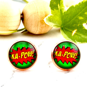 All Up In The Hair | Online Accessory Boutique Located in Mooresville, NC | Two Comic Ka-Pow Earrings on a white marble background. Behind the earrings is a wood bead garland and ivy leaves.