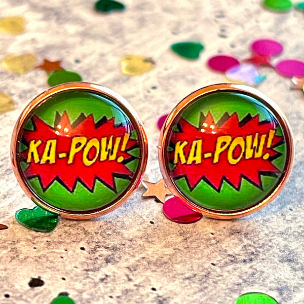 All Up In The Hair | Online Accessory Boutique Located in Mooresville, NC | Two Comic Ka-Pow Earrings laying on a gray background, surrounded by colorful glitter.