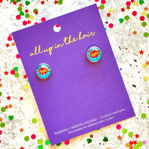 All Up In The Hair | Online Accessory Boutique Located in Mooresville, NC | Two comic pow earrings on an All Up In The Hair branded packaging card. The card is layinng on a gray background, surrounded by colorful glitter.