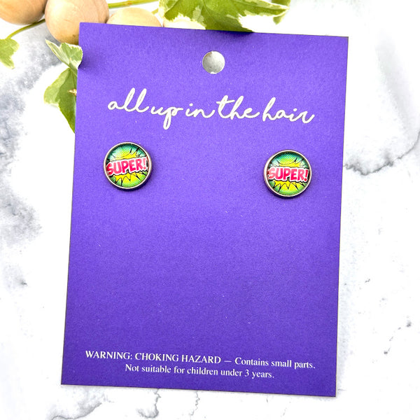 All Up In The Hair | Online Accessory Boutique Located in Mooresville, NC | Two Comic Super Earrings on an indigo colored, All Up In The Hair branded packaging card. The card is laying on a white marble background.