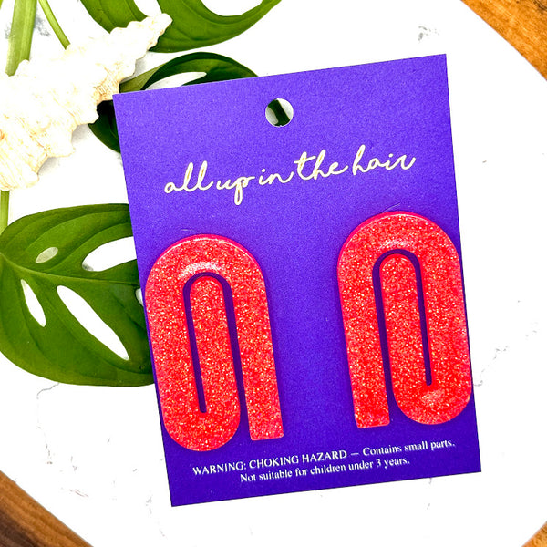 All Up In The Hair | Online Accessory Boutique Located in Mooresville, NC | Two coral paperclip earrings on a backer card. The card is laying on a white background. Behind the card is some monstera leaves and a shell.