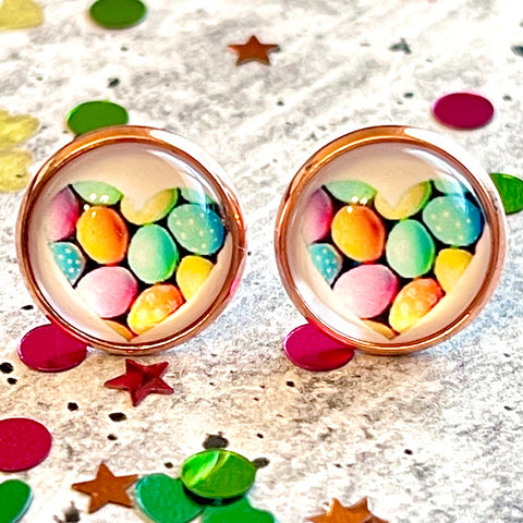 All Up In The Hair | Online Accessory Boutique Located in Mooresville, NC | Two Easter Egg earrings laying on a gray background, surrounded by colorful glitter.