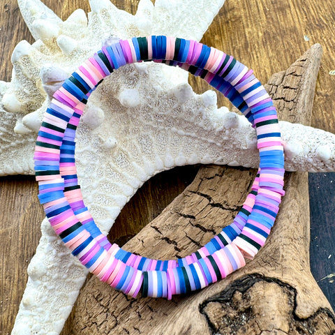 All Up In The Hair | Online Accessory Boutique Located in Mooresville, NC | Two blue, pink, and purple bracelets laying on a piece of driftwood and a white starfish.