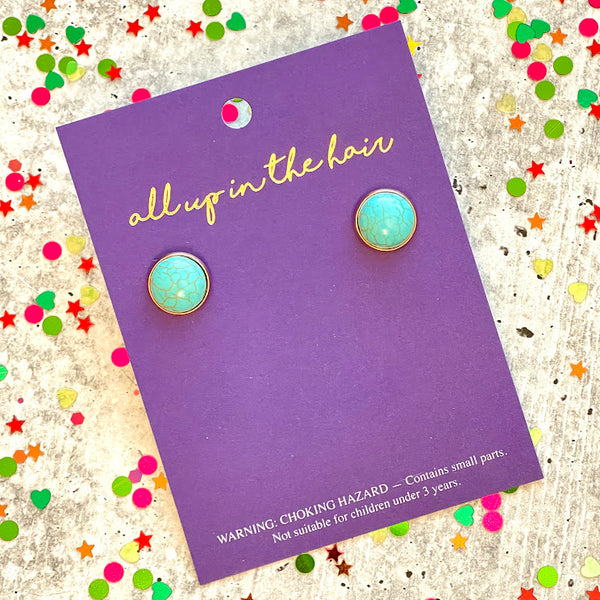 All Up In The Hair | Online Accessory Boutique Located in Mooresville, NC | Two faux turqouise earrings on an All Up In The Hair branded packaging card. The card is laying on a gray background, surrounded by colorful glitter.