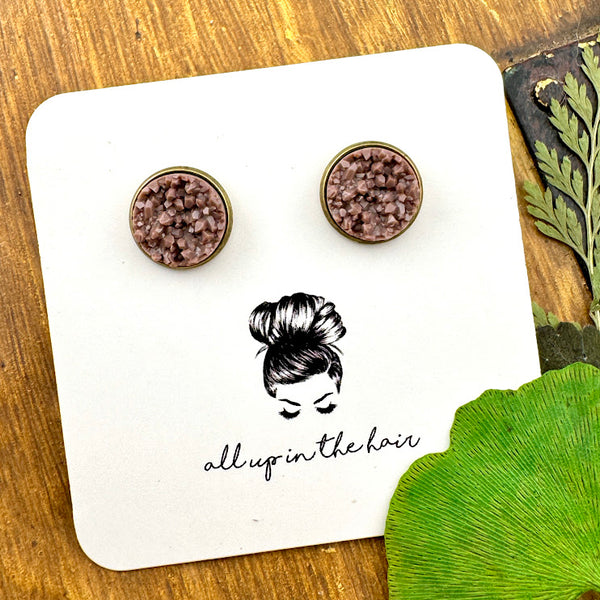 All Up In The Hair | Online Accessory Boutique Located in Mooresville, NC | Two fawn brown druzies set in a bronze earrings setting. The earrings are on a white, All Up In The Hair branded packaging card. The card is laying on a wood background alongside green leaves.