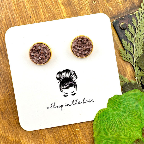 All Up In The Hair | Online Accessory Boutique Located in Mooresville, NC | Two fawn brown druzies set in a gold earrings setting. The earrings are on a white, All Up In The Hair branded packaging card. The card is laying on a wood background alongside green leaves.