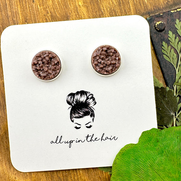 All Up In The Hair | Online Accessory Boutique Located in Mooresville, NC | Two fawn brown druzies set in a silver earrings setting. The earrings are on a white, All Up In The Hair branded packaging card. The card is laying on a wood background alongside green leaves.