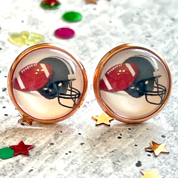 All Up In The Hair | Online Accessory Boutique Located in Mooresville, NC | Two football earrings laying on a gray background, surrounded by colorful glitter.