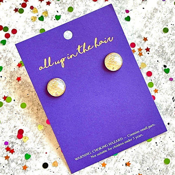 All Up In The Hair | Online Accessory Boutique Located in Mooresville, NC | Two frost mermaid earrings on an All Up In The Hair branded packaging card. The card is laying on a gray background, surrounded by colorful glitter.