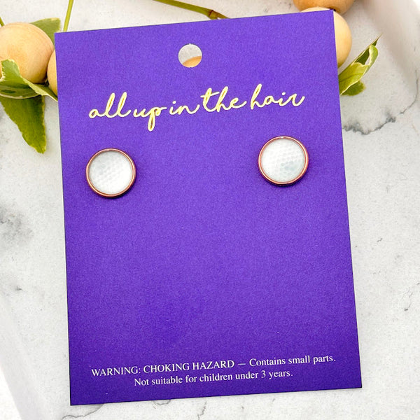 All Up In The Hair | Online Accessory Boutique Located in Mooresville, NC | Two Golf Ball Earrings on an indigo colored, All Up In The Hair branded packaging card. The card is laying on a white marble background alongside a wood bead garland and ivy leaves.