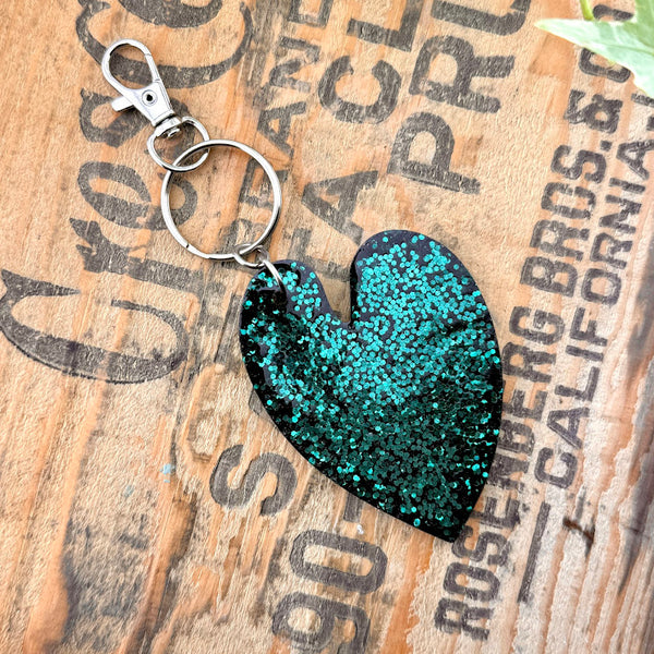 All Up In The Hair | Online Accessory Boutique Located in Mooresville, NC | Back of our Heart Leaf Philodendron Keychain on a wood background with black lettering. 