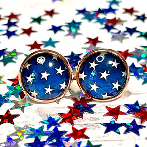 All Up In The Hair | Online Accessory Boutique Located in Mooresville, NC | Two Star Earrings laying on a white background. The background is covered with red, white, and blue, confetti stars.