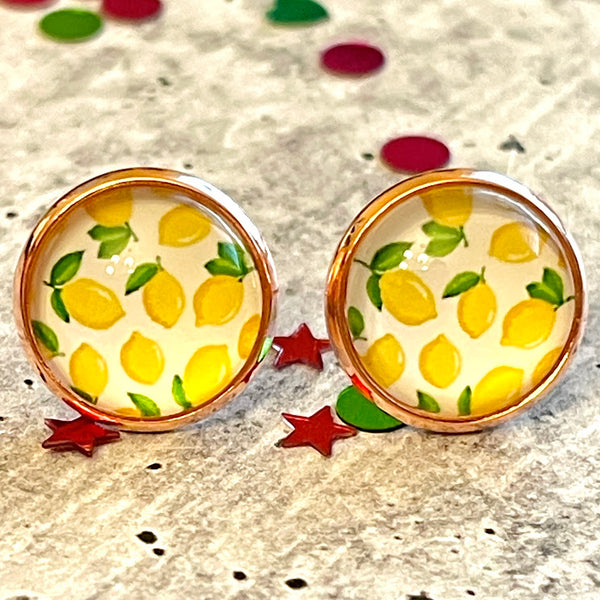 All Up In The Hair | Online Accessory Boutique Located in Mooresville, NC | Two lemon print stud earrings laying on a gray background, surrounded by colorful glitter.