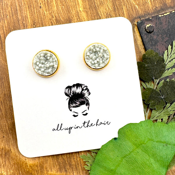 All Up In The Hair | Online Accessory Boutique Located in Mooresville, NC | Two light grey druzy cabochons in a gold setting on a white, All Up In The Hair branded packaging card. The card is laying on a wood background next to leaves.