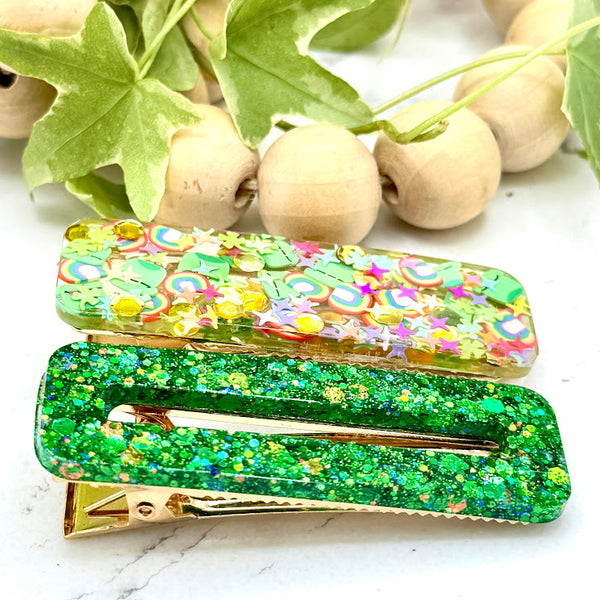 All Up In The Hair | Online Accessory Boutique Located in Mooresville, NC | Side view of our Lucky Barrette Set on a white marble background. At the top of the image is a wood bead garland and ivy leaves.