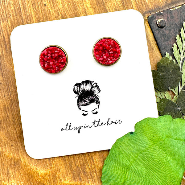 All Up In The Hair | Online Accessory Boutique Located in Mooresville, NC | Two Maroon Druzy in bronze settings on a white, All Up In The Hair branded packaging card. The card is laying on a wood background next to green leaves.