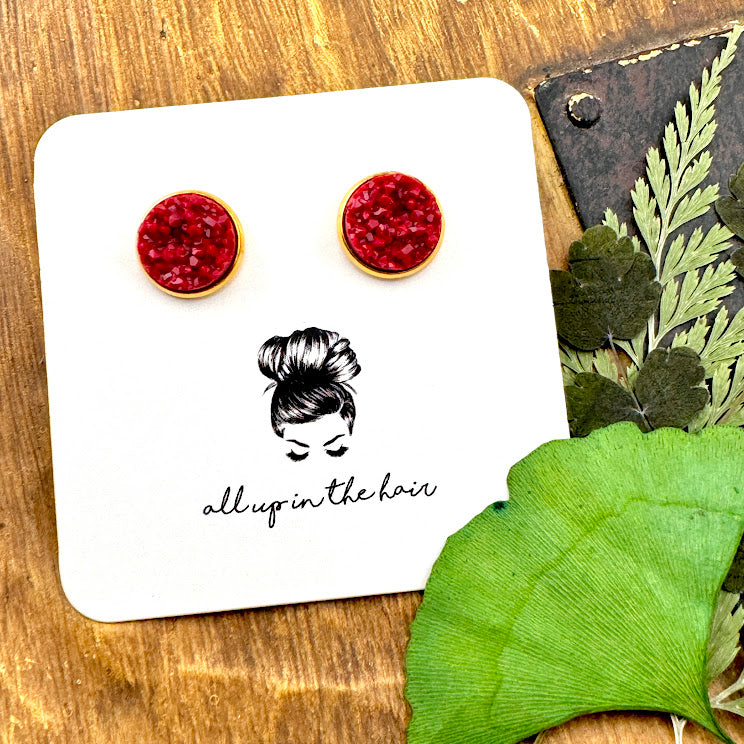 All Up In The Hair | Online Accessory Boutique Located in Mooresville, NC | Two Maroon Druzy in gold settings on a white, All Up In The Hair branded packaging card. The card is laying on a wood background next to green leaves.