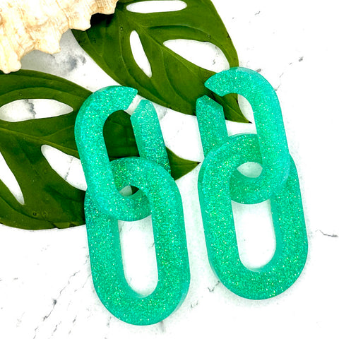 All Up In The Hair | Online Accessory Boutique Located in Mooresville, NC | Two Mint Chain Earrings laying on two monstera leaves on a white marble background.