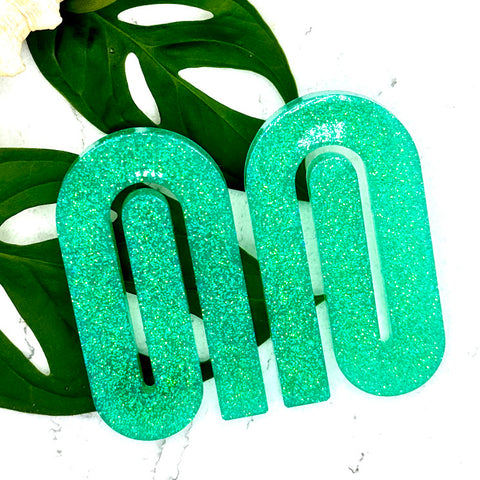 All Up In The Hair | Online Accessory Boutique Located in Mooresville, NC | Two mint paperclip earrings laying on two monstera leaves on a white background.