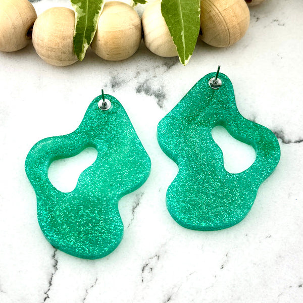 All Up In The Hair | Online Accessory Boutique Located in Mooresville, NC | Back of two Mint Wave Earrings. The earrings are laying on a white marble background. There is a wood bead garland and ivy leaves behind the earrings.