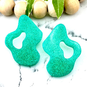 All Up In The Hair | Online Accessory Boutique Located in Mooresville, NC | Two Mint Wave Earrings on a white marble background. There is a wood bead garland and ivy leaves behind the earrings.