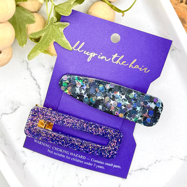 All Up In The Hair | Online Accessory Boutique Located in Mooresville, NC | Our Nova Barrette Set on an indigo colored, All Up In The Hair branded packaging card. The card is laying on a white marble background. At the top of the picture is a wood bead chain and ivy leaves.