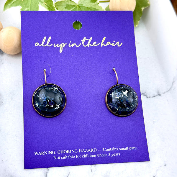 All Up In The Hair | Online Accessory Boutique Located in Mooresville, NC | Two Nova Dangle Earrings on an indigo colored, All Up In The Hair branded packaging card. The card is laying on a white marble background.