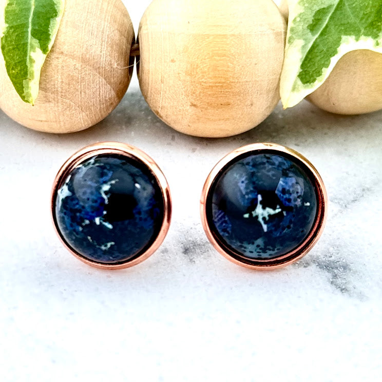 All Up In The Hair | Online Accessory Boutique Located in Mooresville, NC | Two black glitter earrings with silver stars on a white marble background. Behind the earrings is a wood bead garland and ivy leaves.