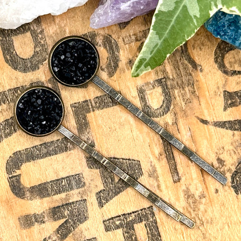 All Up In The Hair | Online Accessory Boutique Located in Mooresville, NC | Two black druzy bobby pins on a wood background with black lettering. There are crystals and ivy leaves at the top of the image.