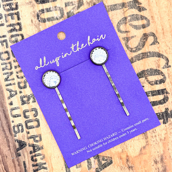 All Up In The Hair | Online Accessory Boutique Located in Mooresville, NC | Two Silver Mermaid Bobby Pins on an indigo colored, All Up In The Hair branded packaging card. The card is laying on a wood background with black lettering.