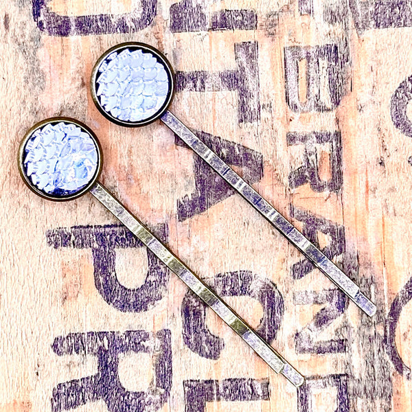 All Up In The Hair | Online Accessory Boutique Located in Mooresville, NC | Silver Mermaid Bobby Pins laying on a wood background with black lettering.