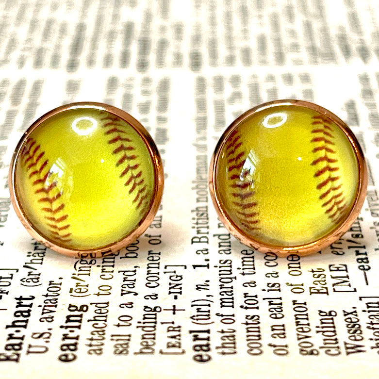 All Up In The Hair | Online Accessory Boutique Located in Mooresville, NC | Close up of two yellow softball earrings laying on a book page.