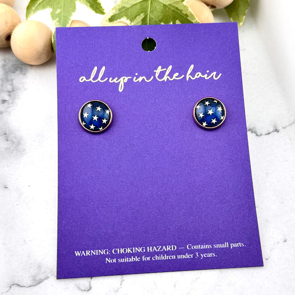 All Up In The Hair | Online Accessory Boutique Located in Mooresville, NC | Two Star Earrings on an indigo colored, All Up In The Hair branded packaging card. The card is laying on a white marble background.