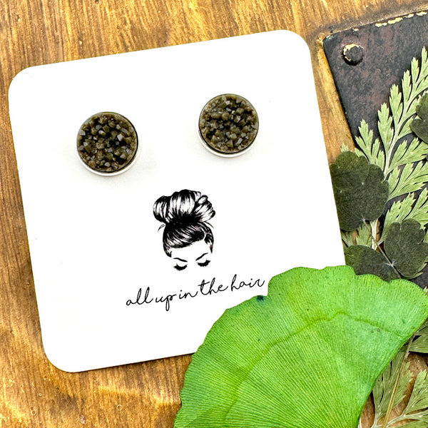 All Up In The Hair | Online Accessory Boutique Located in Mooresville, NC | Two dark grey druzies set in silver settings. The earrings are on a white, All Up In The Hair branded packaging card. The card is laying on a wood background alongside green leaves.