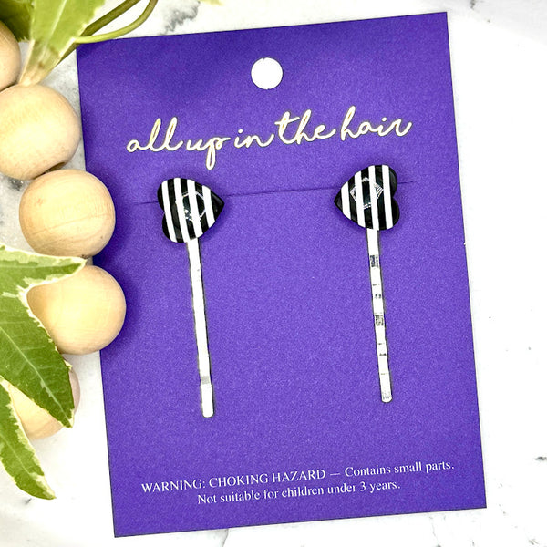 All Up In The Hair | Online Accessory Boutique Located in Mooresville, NC | Two Stripe Heart Bobby Pins on an indigo colored, All Up In The Hair branded packaging card. The card is laying on a white marble background alongside a wood bead garland and ivy leaves.