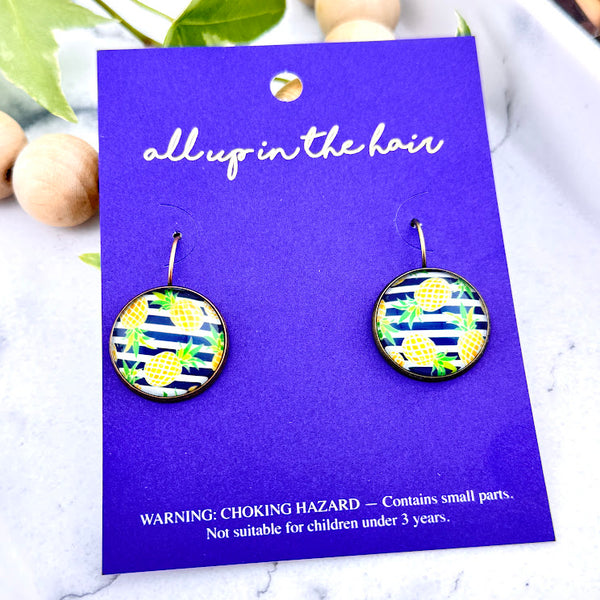 All Up In The Hair | Online Accessory Boutique Located in Mooresville, NC | Two Stripe Pineapple Earrings on an indigo colored, All Up In The Hair branded packaging card. The card is laying on a white marble background.