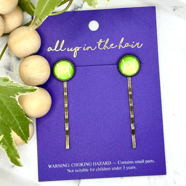 All Up In The Hair | Online Accessory Boutique Located in Mooresville, NC | Two Tennis Bobby Pins on an indigo colored, All Up In The Hair branded packaging card. The card is laying on a white marble background alongside a wood bead garland and ivy leaves.