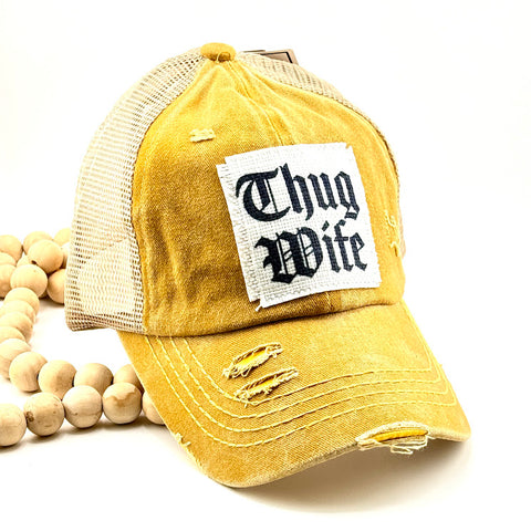 All Up In The Hair | Online Accessory Boutique Located in Mooresville, NC | A mustard yellow baseball cap on a white background. The hat has a white patch with black lettering that says "Thug Wife".