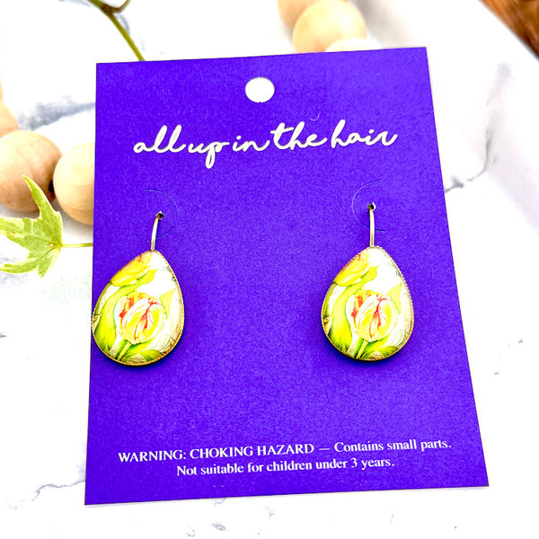 All Up In The Hair | Online Accessory Boutique Located in Mooresville, NC | Two Yellow Tulip Dangle Earrings on an indigo colored, All Up In The Hair branded packaging card. The card is laying on a white marble background.